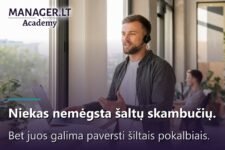 Pardavimų specialistas su ausine kalba telefonu prie lango biure