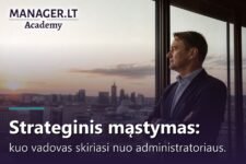 Vadovas žvelgia pro langą į miesto panoramą saulėlydžio metu